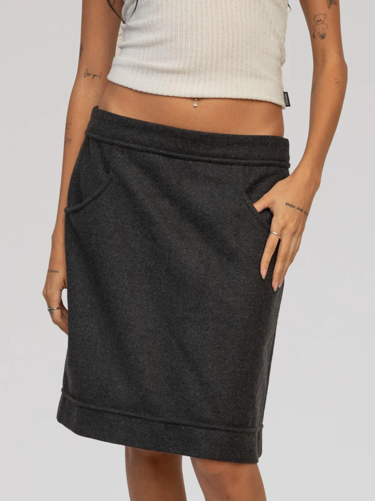 Chanel charcoal grey wool knee-length A-line skirt featuring curved front scoop pockets, structured wide waistband and hem detailing, and side vertical pleats adorned with embossed silver-tone CC logo buttons down the hips.
