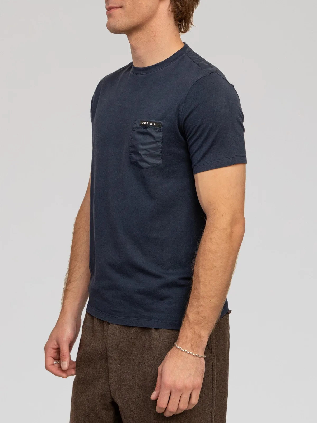 Prada navy blue cotton t-shirt featuring a crew neck, short sleeves, and a tonal nylon chest patch pocket accented with a black leather logo tag.