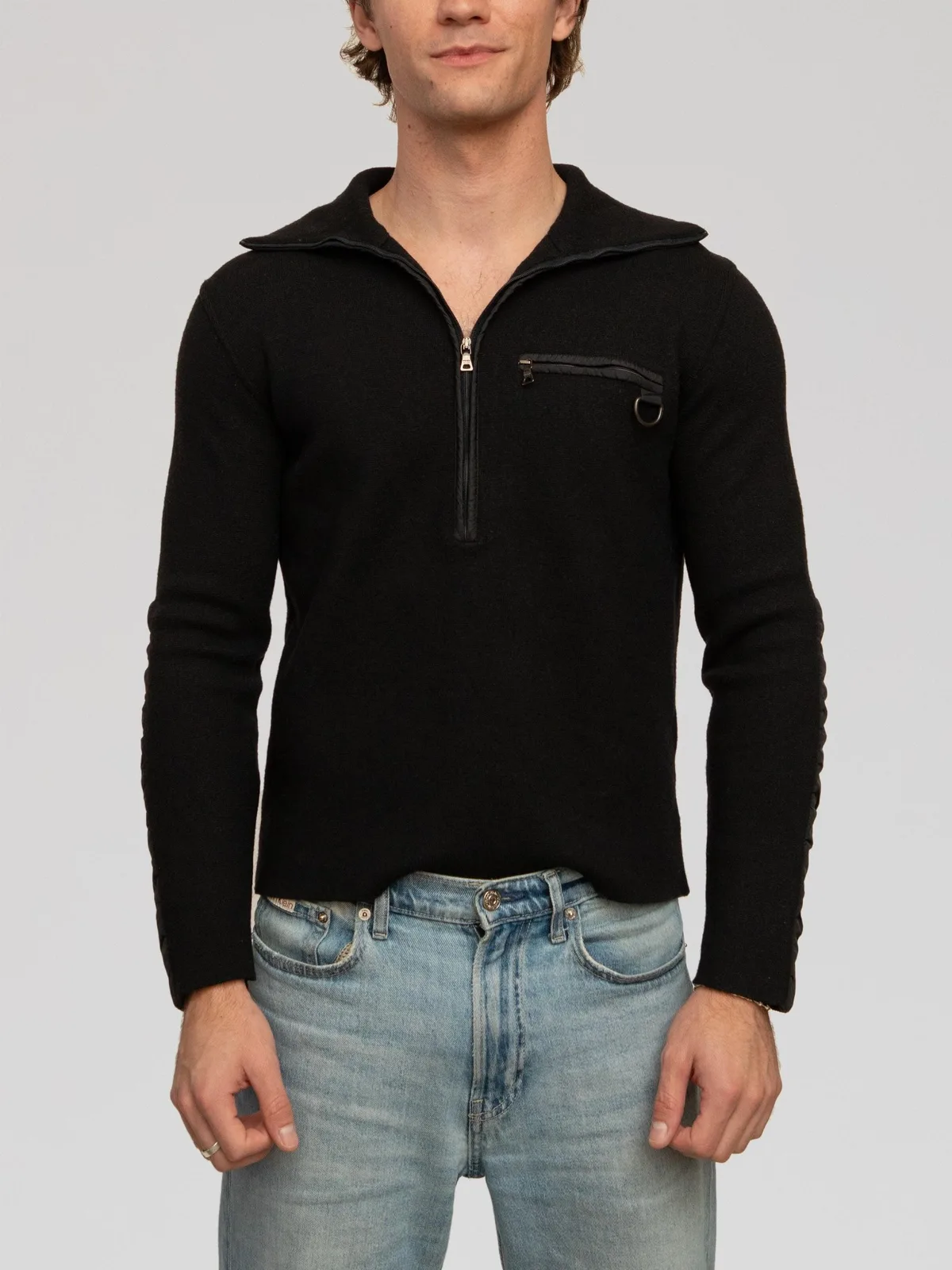 Prada Sport black virgin wool quarter-zip sweater featuring a wide collar, zippered chest pocket with D-ring detail, contrast nylon forearm paneling, and iconic red tab logo branding.