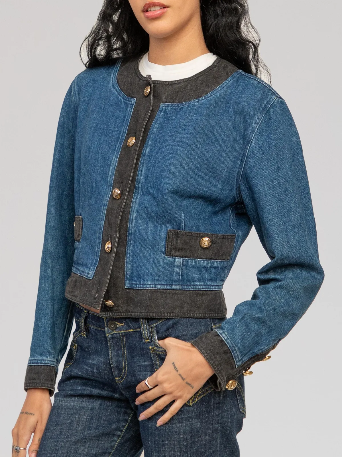 Two-tone Moschino denim jacket featuring a collarless round neckline, contrast dark grey washed denim trim along the placket, collar, hem, and cuffs, dual front flap pockets with gold-tone branded buttons, a button-down front closure, and buttoned sleeve cuffs.